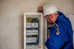 Image is an electrician fixing a breaker box.